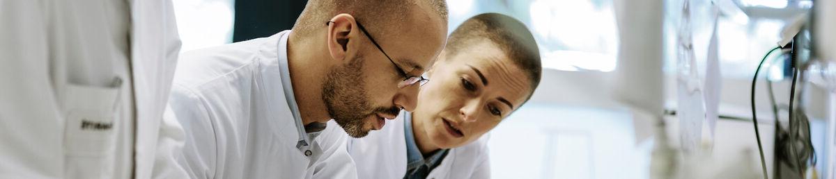 Three scientists leaning over a lab desk looking at something together